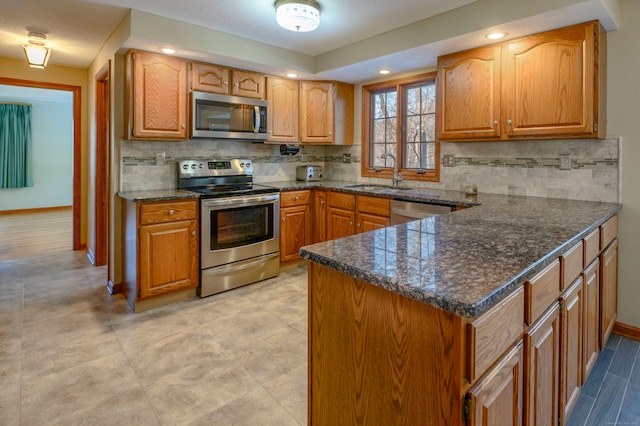 kitchen featuring kitchen peninsula, appliances with stainless steel finishes, tasteful backsplash, sink, and dark stone countertops