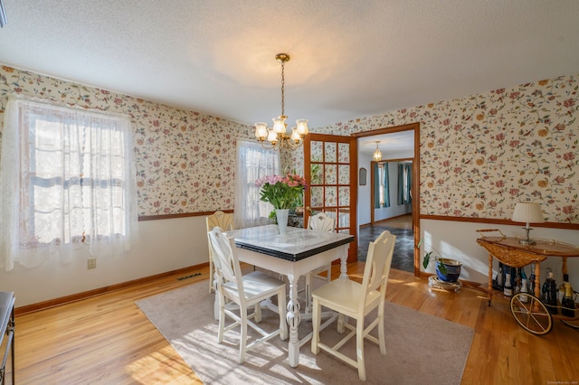 dining space featuring hardwood / wood-style floors, a textured ceiling, and a notable chandelier