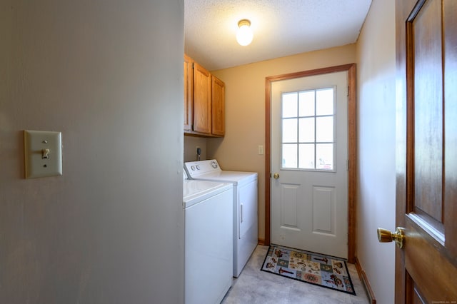 laundry area featuring cabinets, a textured ceiling, and washing machine and clothes dryer