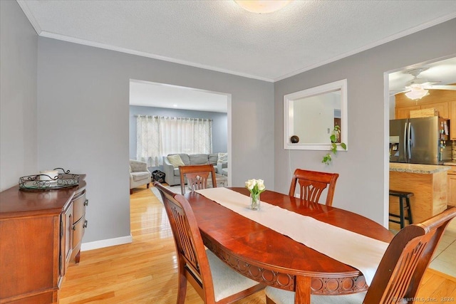 dining room featuring a textured ceiling, light wood-type flooring, ceiling fan, and crown molding