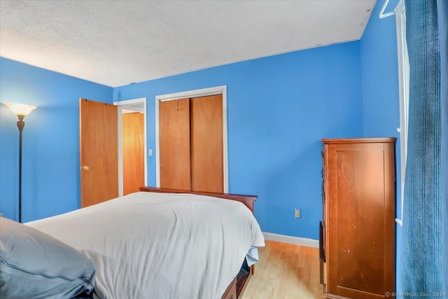 bedroom featuring a closet, light hardwood / wood-style flooring, and a textured ceiling