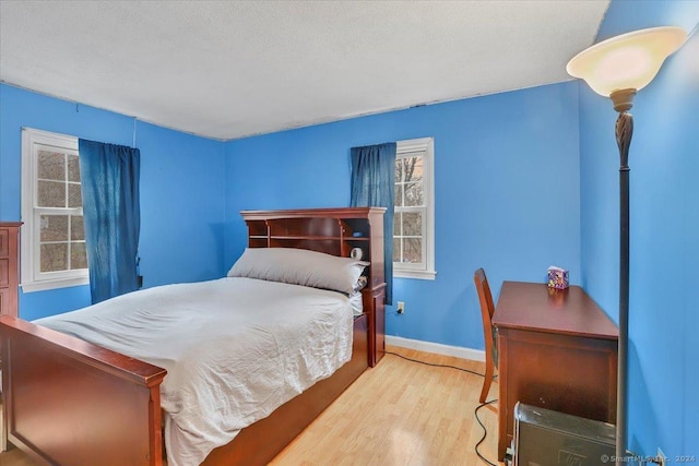 bedroom with light hardwood / wood-style floors and a textured ceiling