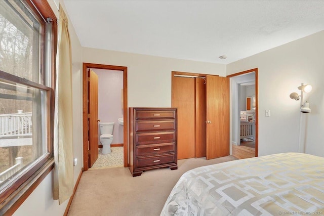 bedroom with light colored carpet, multiple windows, connected bathroom, and a closet