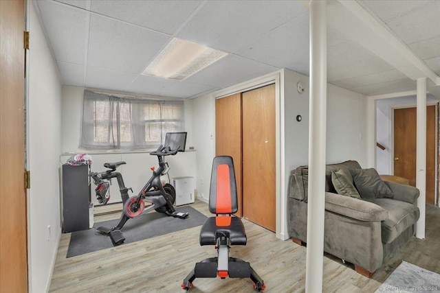 workout area with light wood-type flooring and a drop ceiling