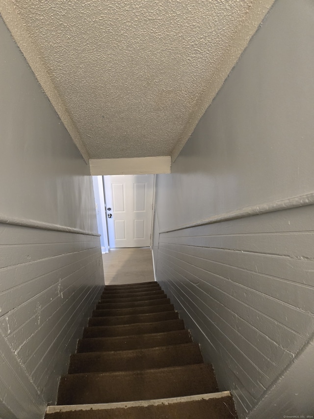 stairway featuring a textured ceiling