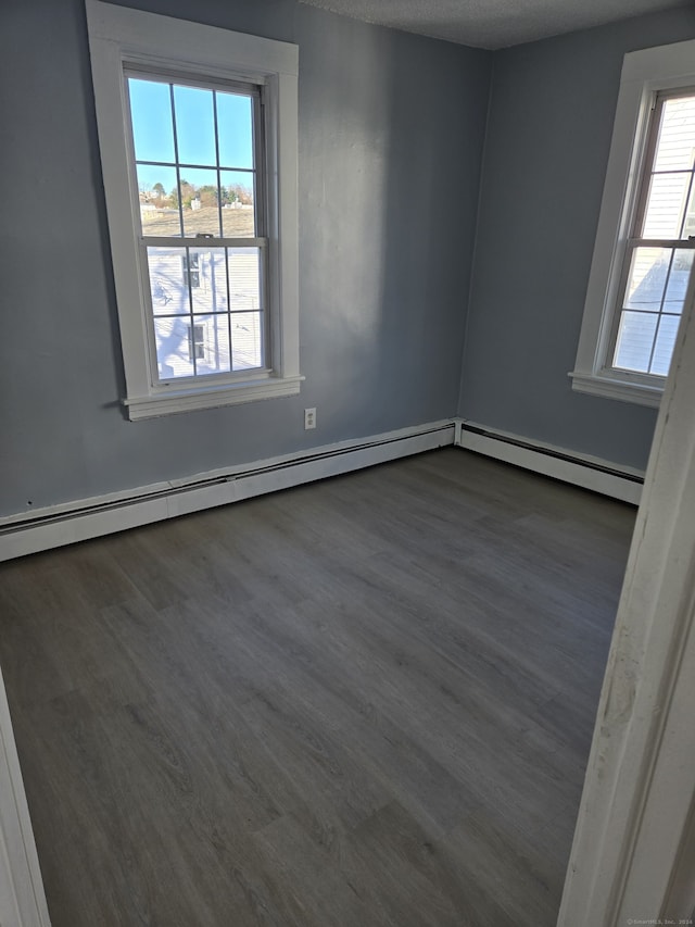 unfurnished room with a textured ceiling, dark hardwood / wood-style floors, and baseboard heating