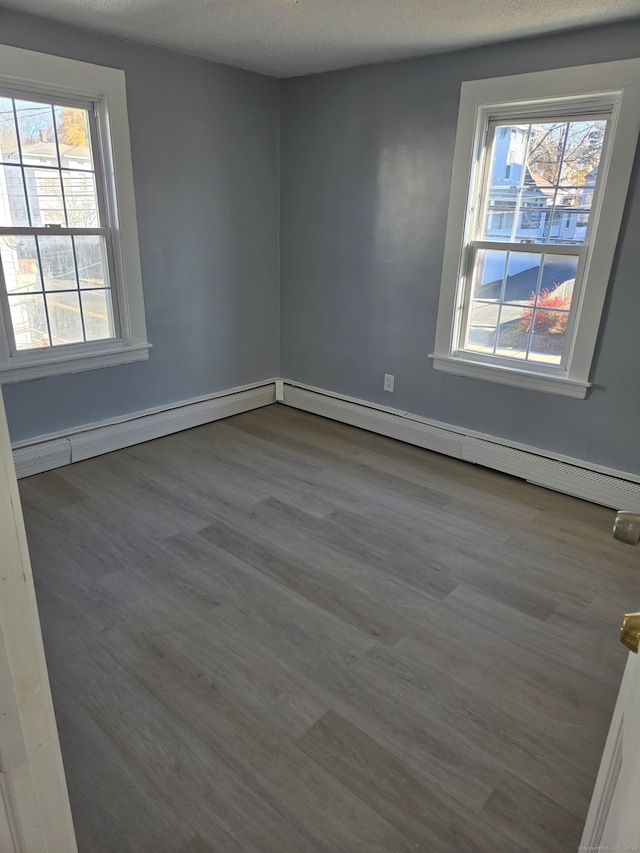 empty room with hardwood / wood-style floors, a textured ceiling, and a wealth of natural light