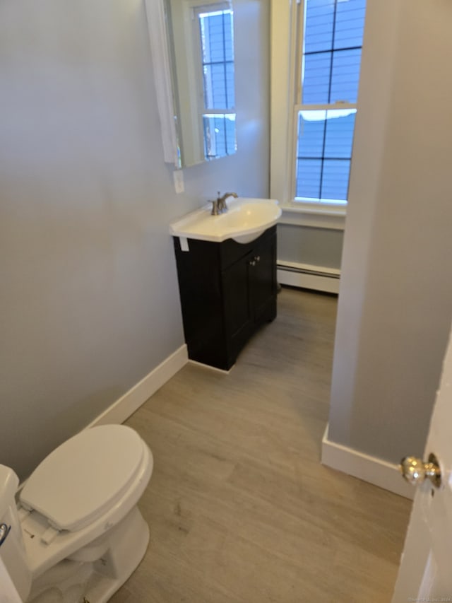 bathroom with hardwood / wood-style floors, vanity, toilet, and a baseboard radiator