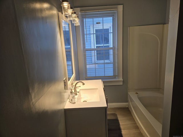 bathroom with hardwood / wood-style flooring, vanity, and shower / washtub combination