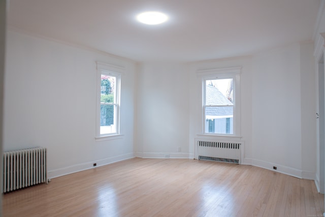 spare room with radiator heating unit, ornamental molding, and light hardwood / wood-style flooring