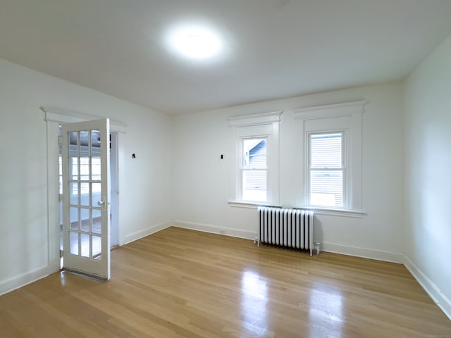 spare room with radiator heating unit and light wood-type flooring