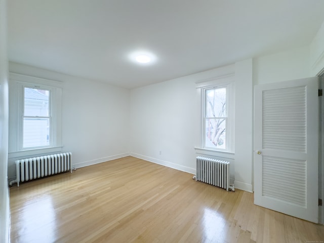 unfurnished room featuring radiator and light hardwood / wood-style flooring