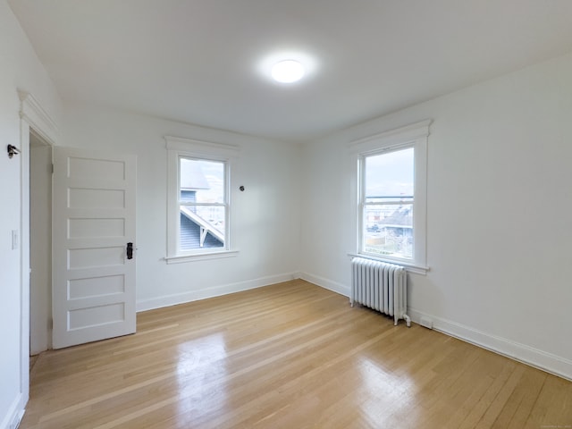 spare room featuring radiator heating unit and light wood-type flooring