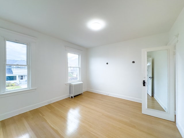 empty room featuring radiator heating unit and light hardwood / wood-style floors