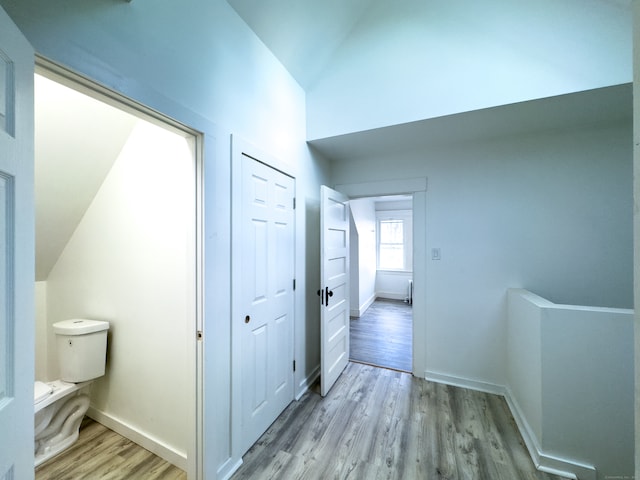 hallway with light wood-type flooring and vaulted ceiling