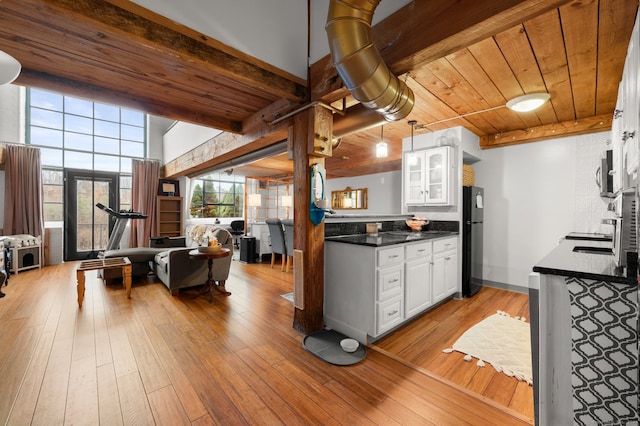 kitchen featuring black fridge, light hardwood / wood-style flooring, beamed ceiling, white cabinets, and wood ceiling