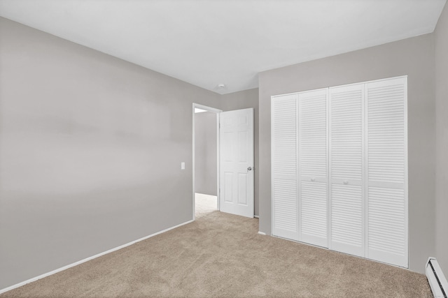 unfurnished bedroom featuring light colored carpet, baseboard heating, and a closet