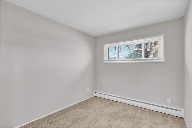 carpeted spare room featuring a baseboard heating unit