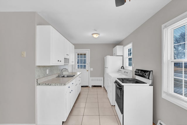 kitchen featuring a baseboard heating unit, white cabinets, sink, light tile patterned floors, and white range with electric stovetop