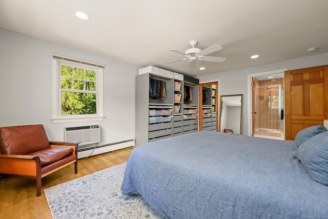 bedroom with ceiling fan, a wall mounted AC, connected bathroom, a baseboard radiator, and light wood-type flooring