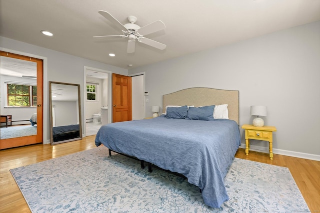 bedroom featuring baseboard heating, ceiling fan, wood-type flooring, and ensuite bathroom