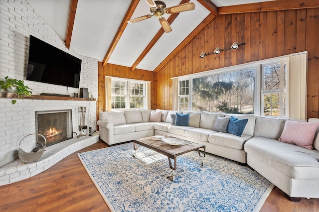 living room with beam ceiling, high vaulted ceiling, wooden walls, a fireplace, and hardwood / wood-style floors