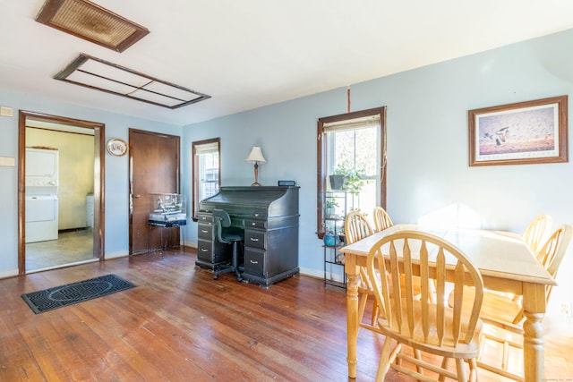 dining space with dark hardwood / wood-style flooring and stacked washer and clothes dryer