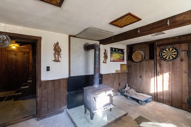 living room with a wood stove and wooden walls