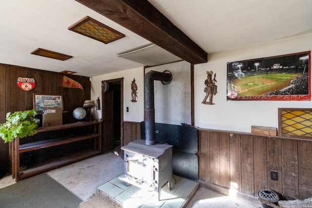 living room with beam ceiling, a wood stove, and wooden walls