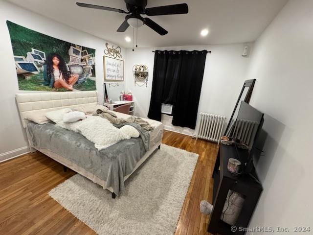 bedroom with radiator heating unit, ceiling fan, and dark wood-type flooring