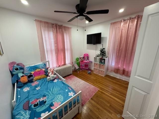 bedroom with ceiling fan, radiator heating unit, and dark wood-type flooring