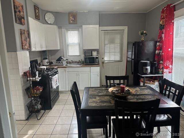 kitchen with white cabinetry, sink, backsplash, light tile patterned floors, and black appliances