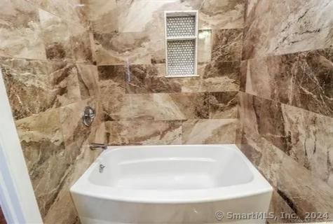 bathroom with a bathtub and tile walls