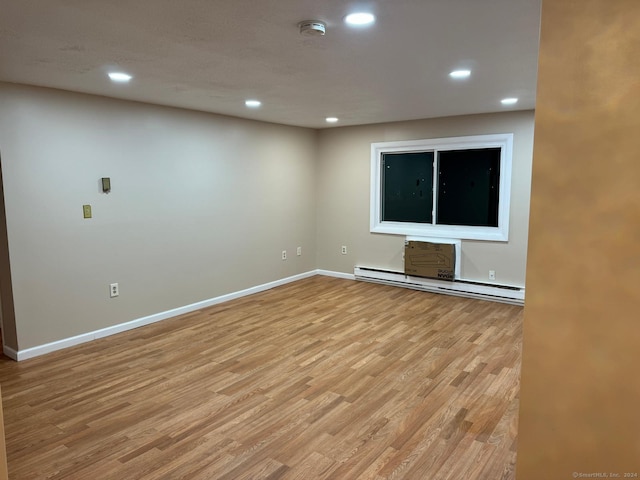 unfurnished room with light wood-type flooring and a baseboard heating unit