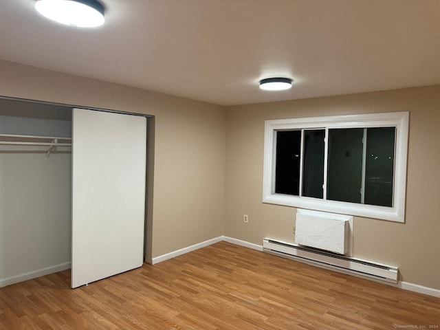 unfurnished bedroom featuring a closet, light hardwood / wood-style flooring, and baseboard heating