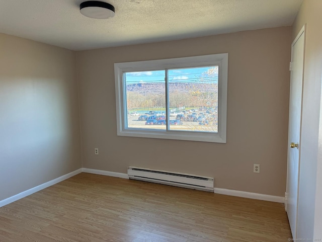 unfurnished room with a textured ceiling, light wood-type flooring, and a baseboard heating unit