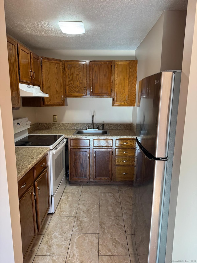 kitchen featuring stainless steel refrigerator, sink, white electric range, light stone counters, and a textured ceiling