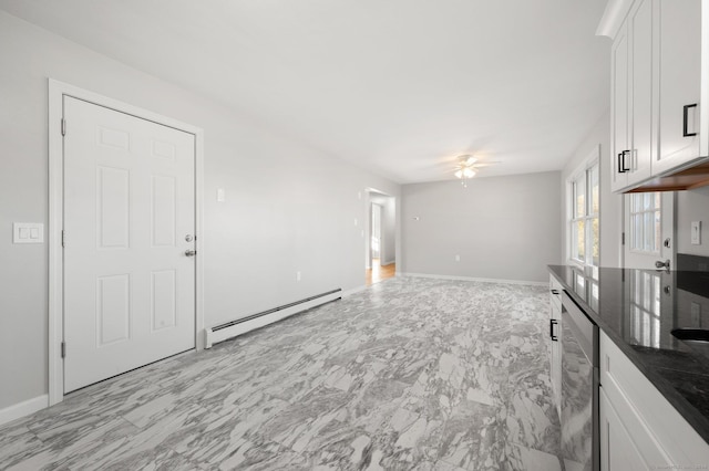 unfurnished living room with ceiling fan and a baseboard heating unit