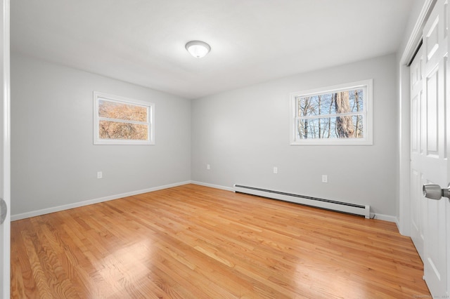 unfurnished room featuring a healthy amount of sunlight, light hardwood / wood-style flooring, and a baseboard heating unit