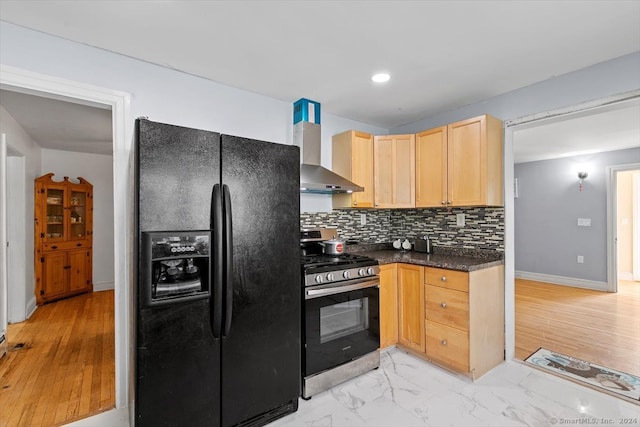 kitchen featuring black fridge with ice dispenser, stainless steel stove, wall chimney range hood, and light hardwood / wood-style flooring