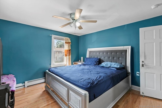 bedroom with light hardwood / wood-style floors, baseboard heating, and ceiling fan