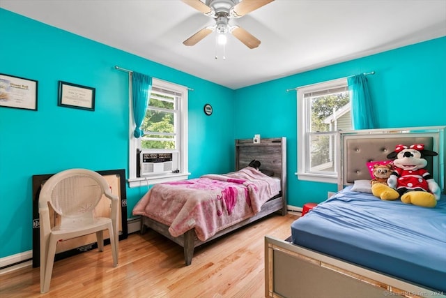 bedroom featuring ceiling fan, light hardwood / wood-style floors, baseboard heating, and cooling unit