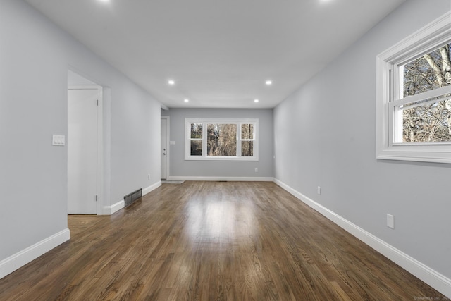 empty room with a healthy amount of sunlight and dark hardwood / wood-style floors