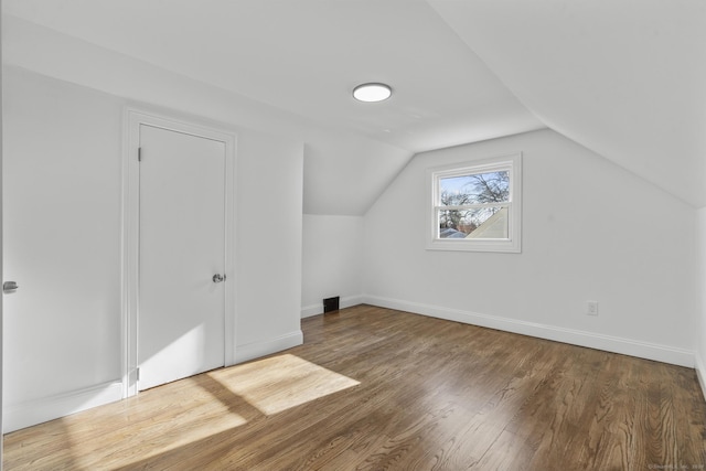 additional living space with hardwood / wood-style floors and lofted ceiling