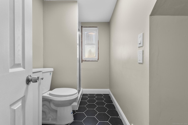 bathroom featuring toilet, tile patterned floors, and a shower with shower door