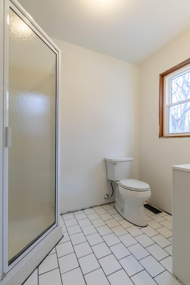 bathroom featuring tile patterned floors, toilet, and walk in shower