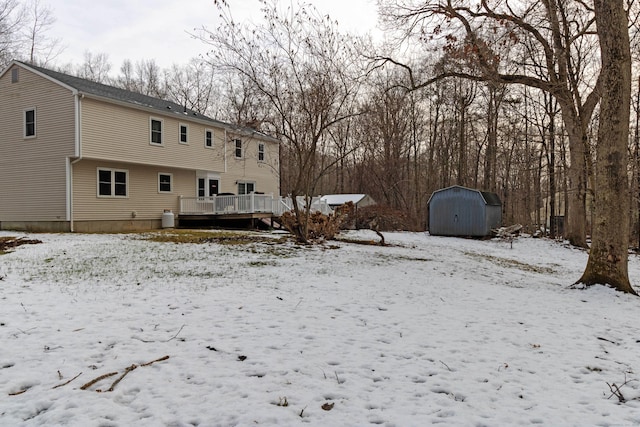 yard covered in snow featuring a shed and a deck