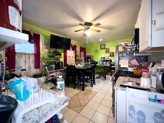 kitchen featuring white range oven, ceiling fan, white cabinets, and light tile patterned floors