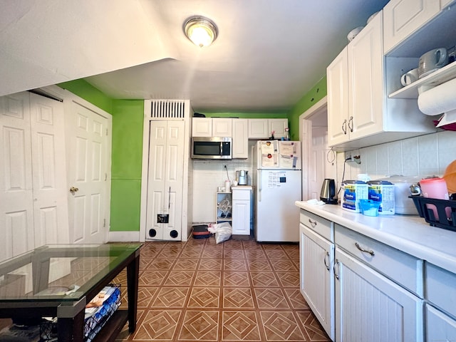 kitchen with backsplash, white cabinetry, and white fridge