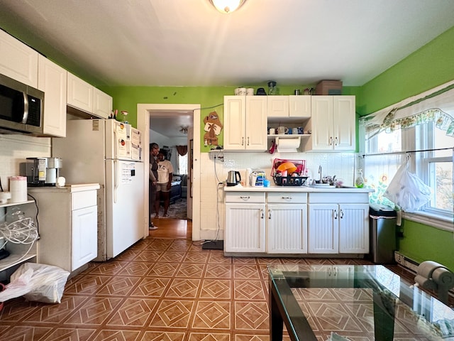 kitchen featuring decorative backsplash, sink, white cabinets, and white refrigerator